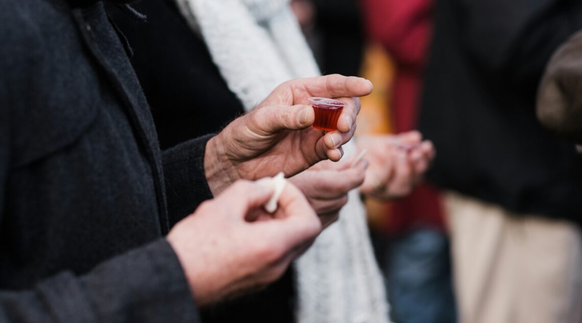 Man met wijn en brood, voor Heilige Avondmaal, in de hand.