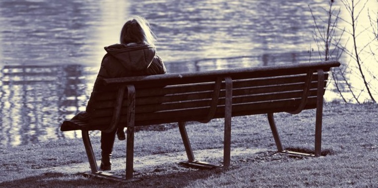 Ondraaglijke stilte Vrouw die op een bankje over het water uitkijkt