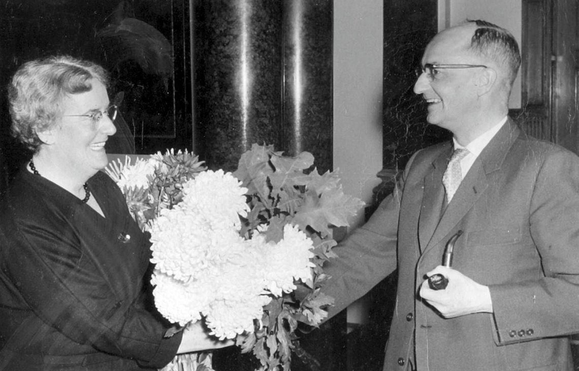 Arnold van Ruler die bloemen overhandigt aan zijn vrouw, bij het afronden van haar studie rechten in 1963