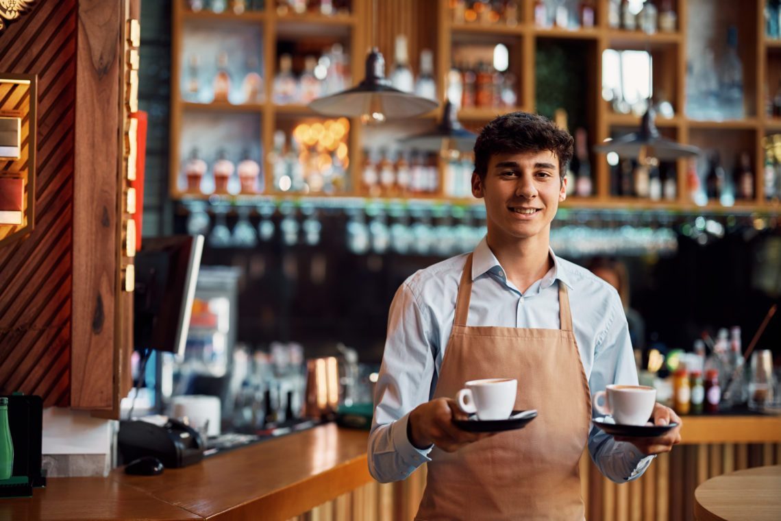 Jonge serveerder die een kopje koffie vasthoudt