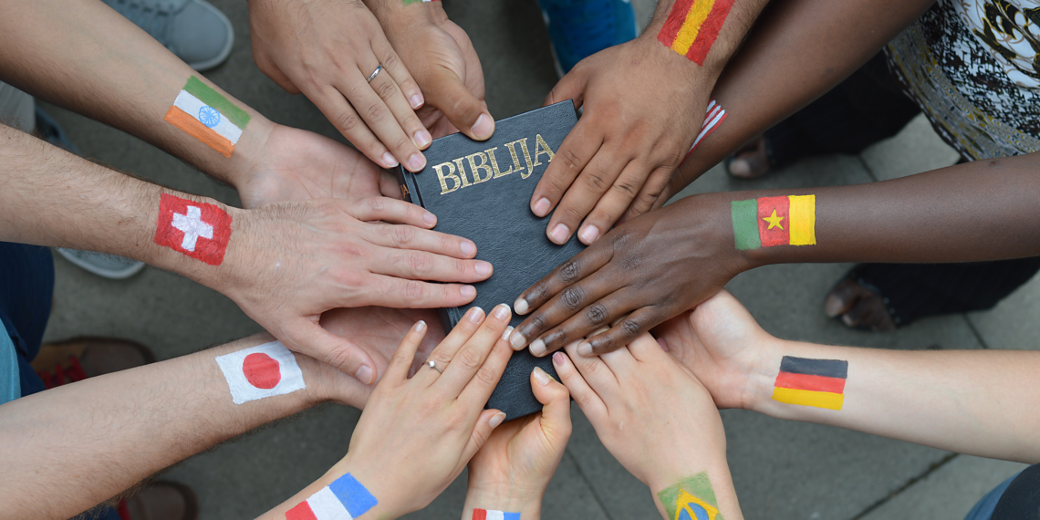 Wereldkerk Handen van mensen van verschillende afkomsten die samenkomen op een Bijbel
