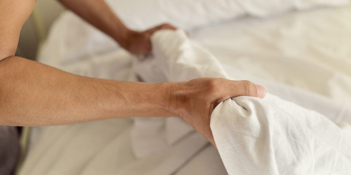 Een jongeman maakt het bed op