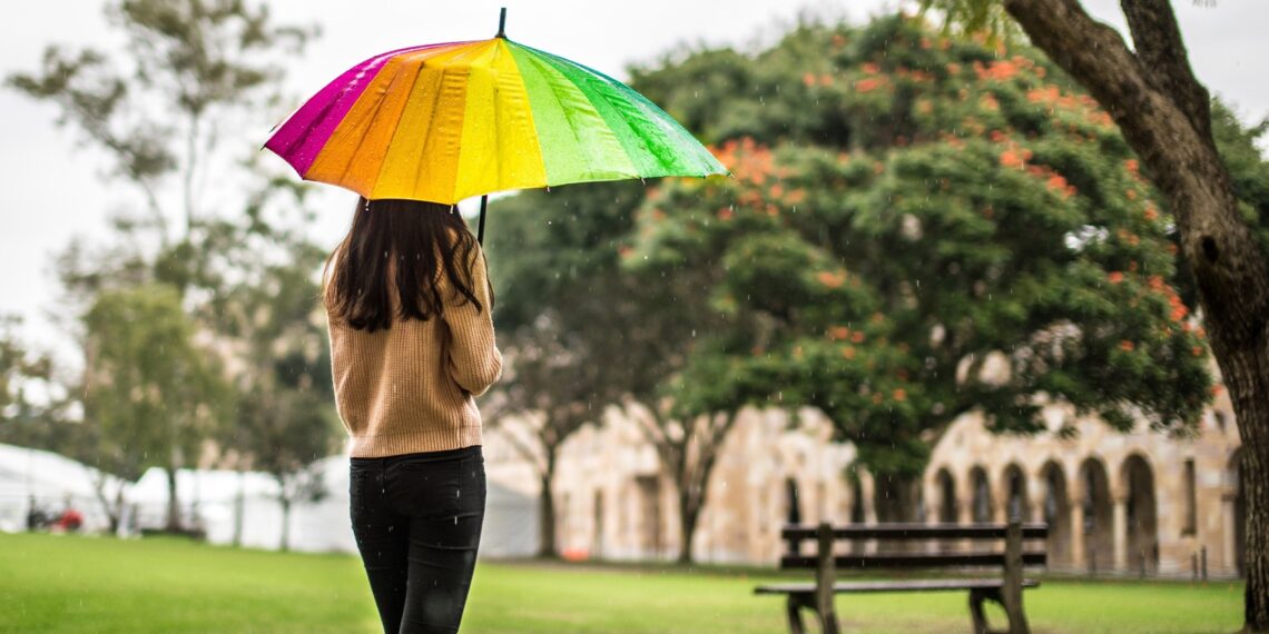 regenboog Vrouw in een park met regenboogparaplu