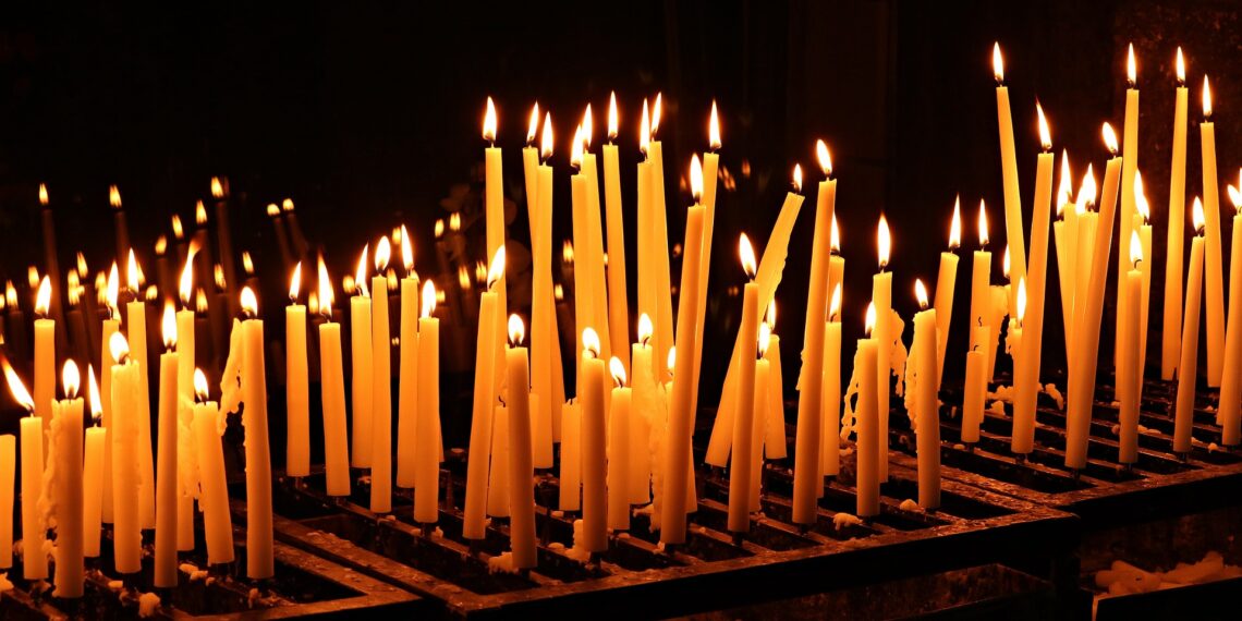 Een rij met hoge kaarsen die aangestoken zijn
