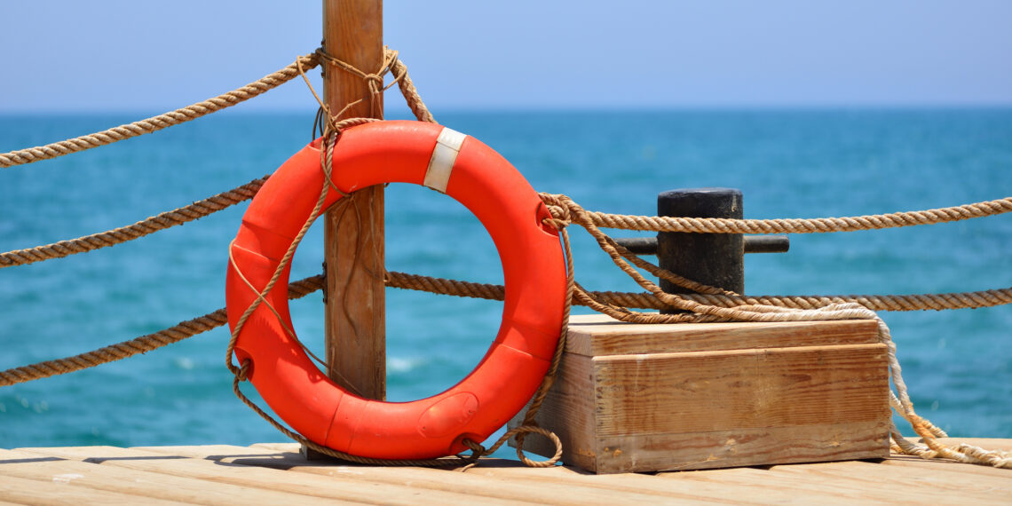 Zeekust met rode reddingsboei en touwen