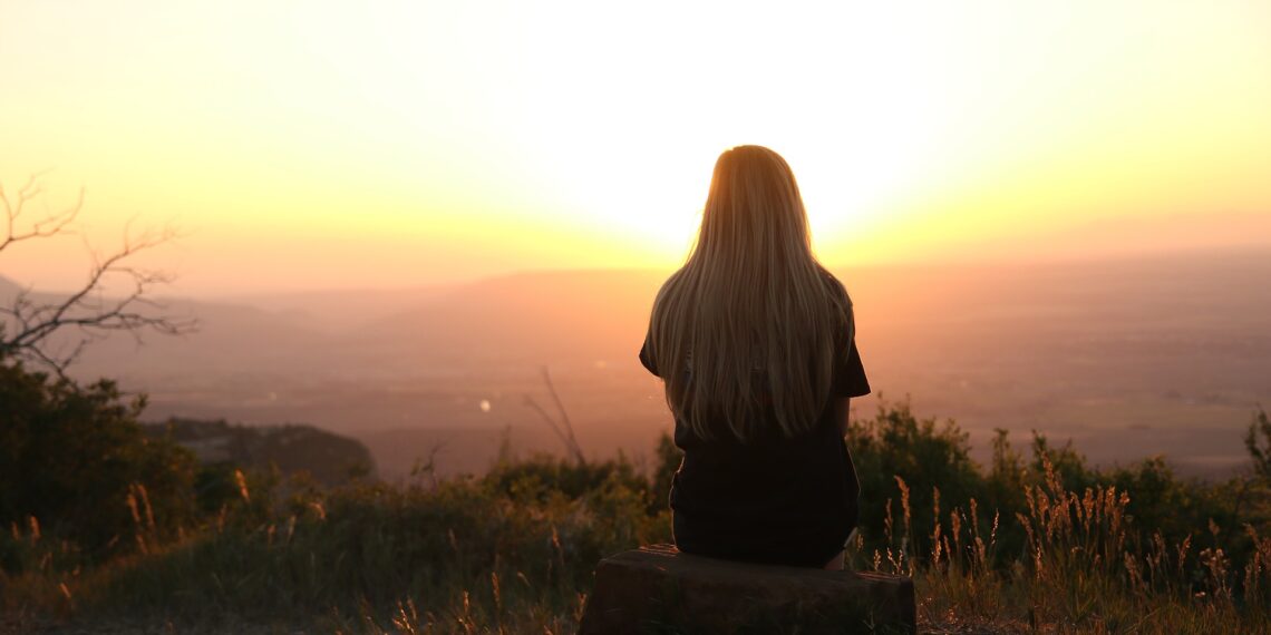Vrouw geniet van uitzicht Vrouw die op een berg zit en geniet van het uitzicht