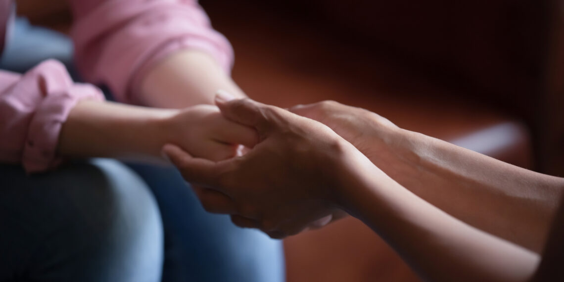 Twee handen die twee andere handen vasthouden Een gesprek waarbij de ene persoon de andere haar handen vast heeft