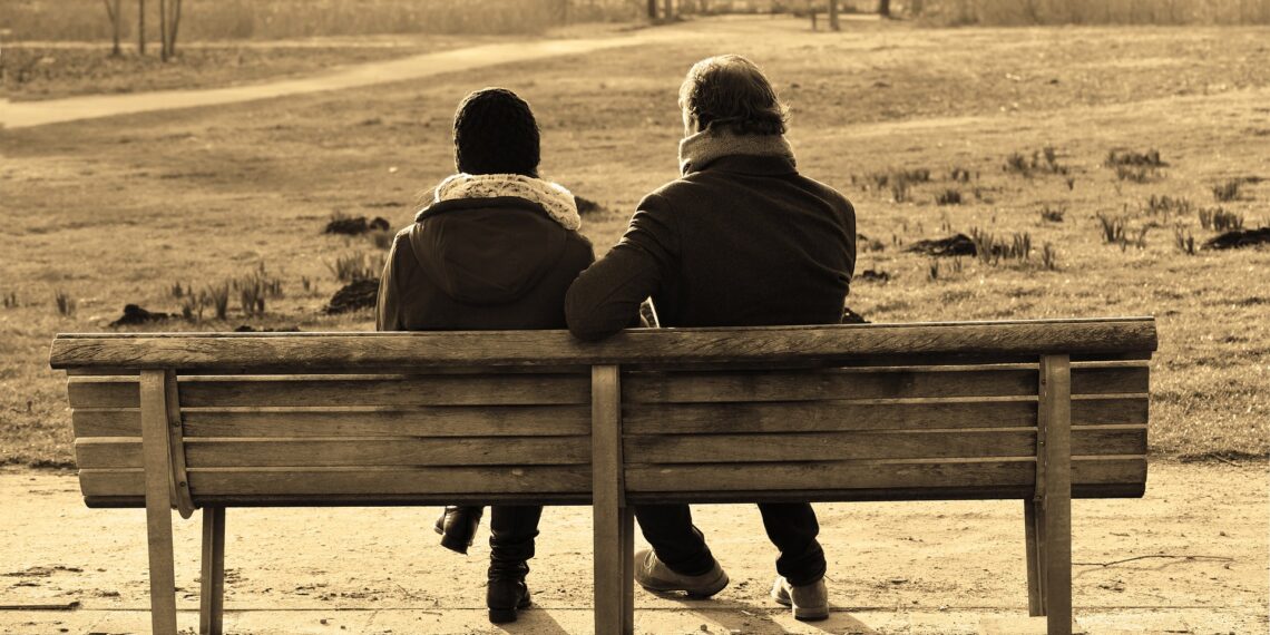 Man en vrouw die buiten een gesprek voeren op een bankje