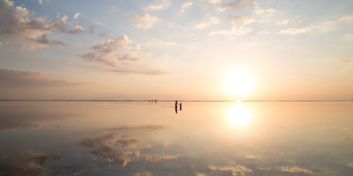 zonsondergang aan het strand. Een groepje mensen zwemt in de zee