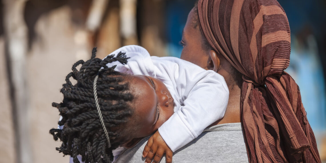 Vrouw met haar kind op haar schouder Afrikaanse vrouw die haar kind op haar schouder draagt