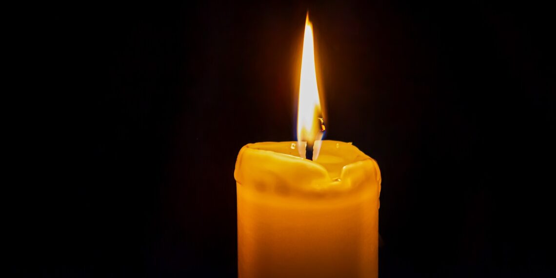 Brandende kaars tegen een zwarte achtergrond.