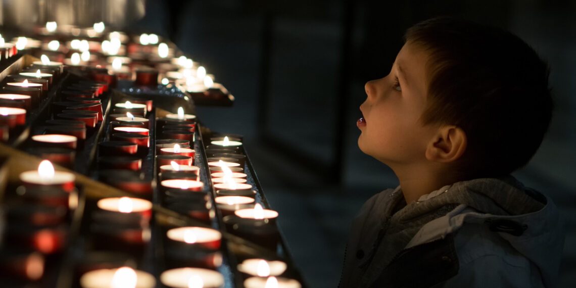 Jongetje bewondert de kaarsjes Jongetje bewondert de kaarsjes in een katholieke kerk