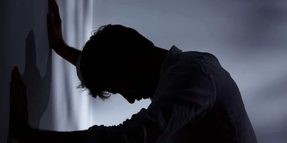 Man tegen de muur aan met zijn handen