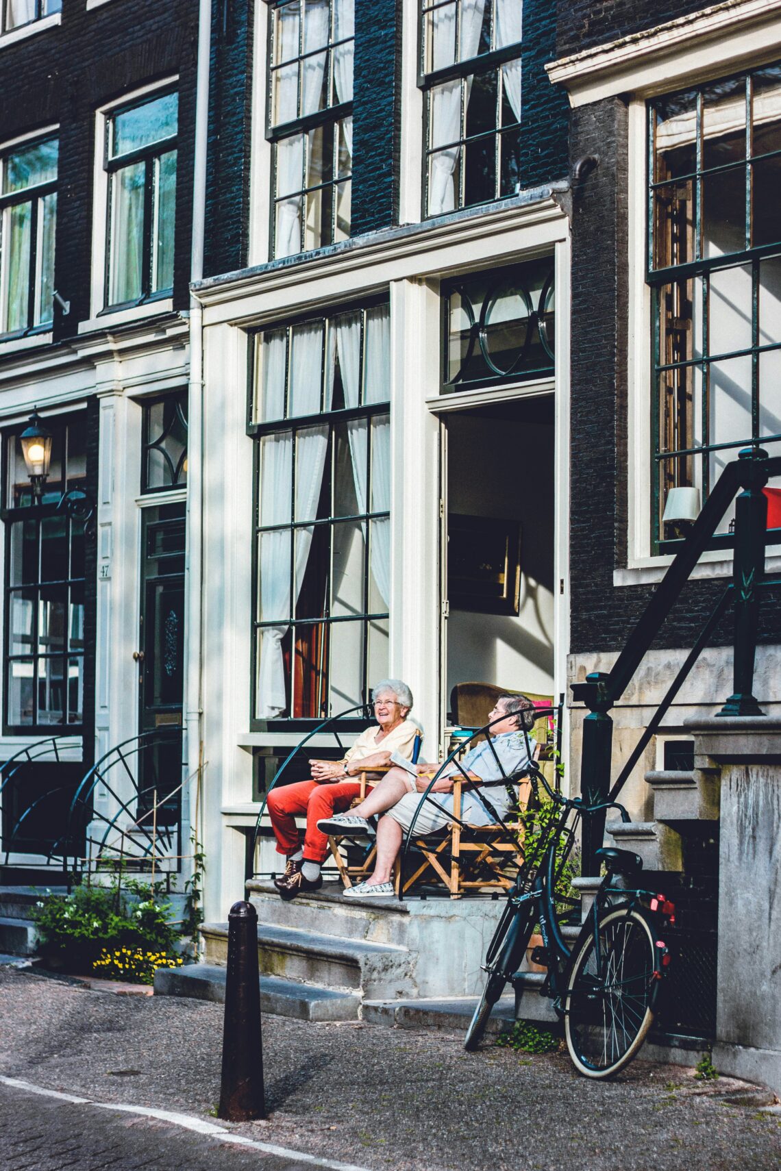 Twee vrouwen die pratend voor een huis zitten in Amsterdam