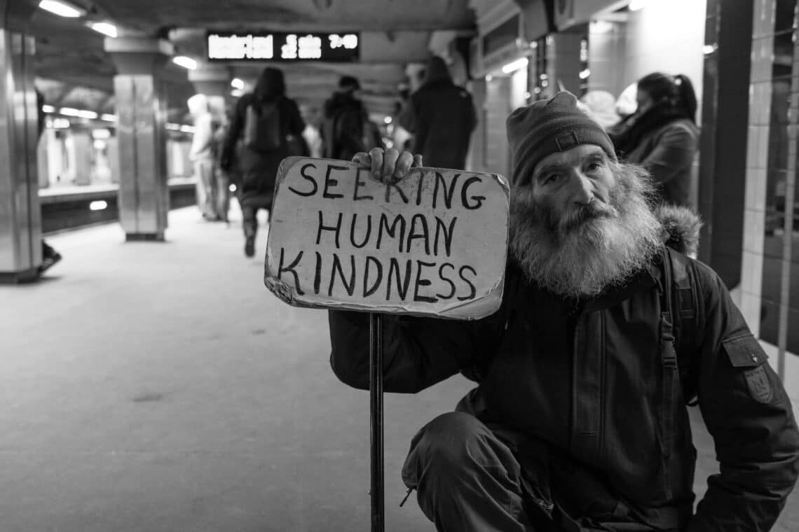Man die een bord vasthoudt met daarop geschreven: 'Seeking human kindness'