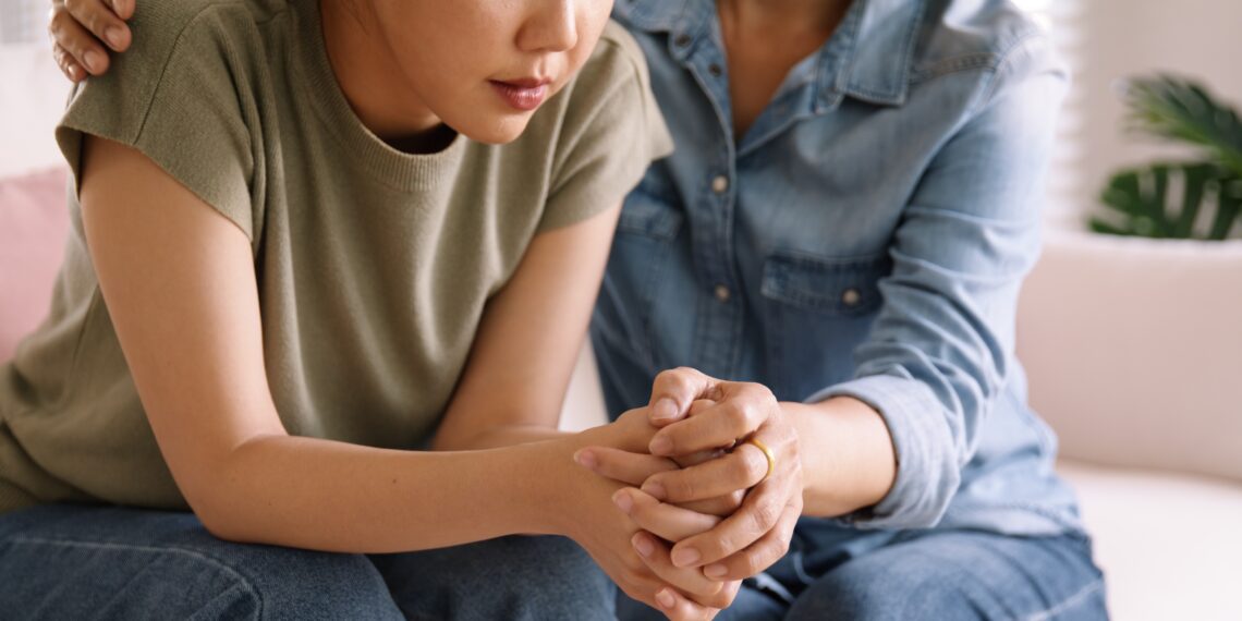 Vrouw troost kind Vrouw troost een kind door de hand vast te houden en een arm om de schouder te slaan
