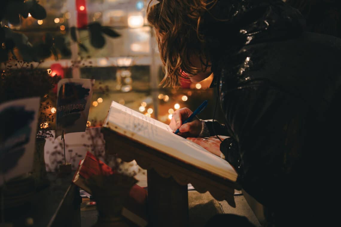 Mensen schrijven een persoonlijk bericht in De glazen kas voor Rouwen en vieren.