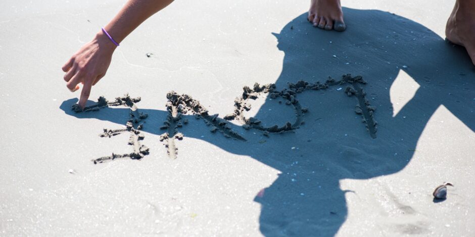 Persoon schrijft 'love' in het zand