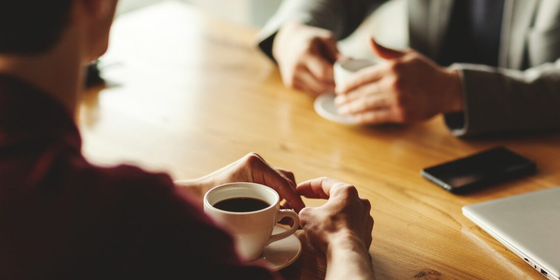 Twee mensen in gesprek met een kop koffie