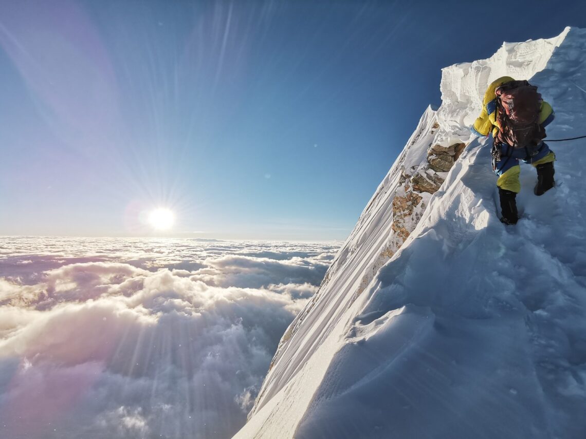Bergbeklimmer die een besneeuwde bergtop aan het beklimmen is