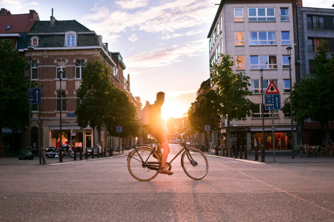 Man die fiets door de stad met zonsondergang