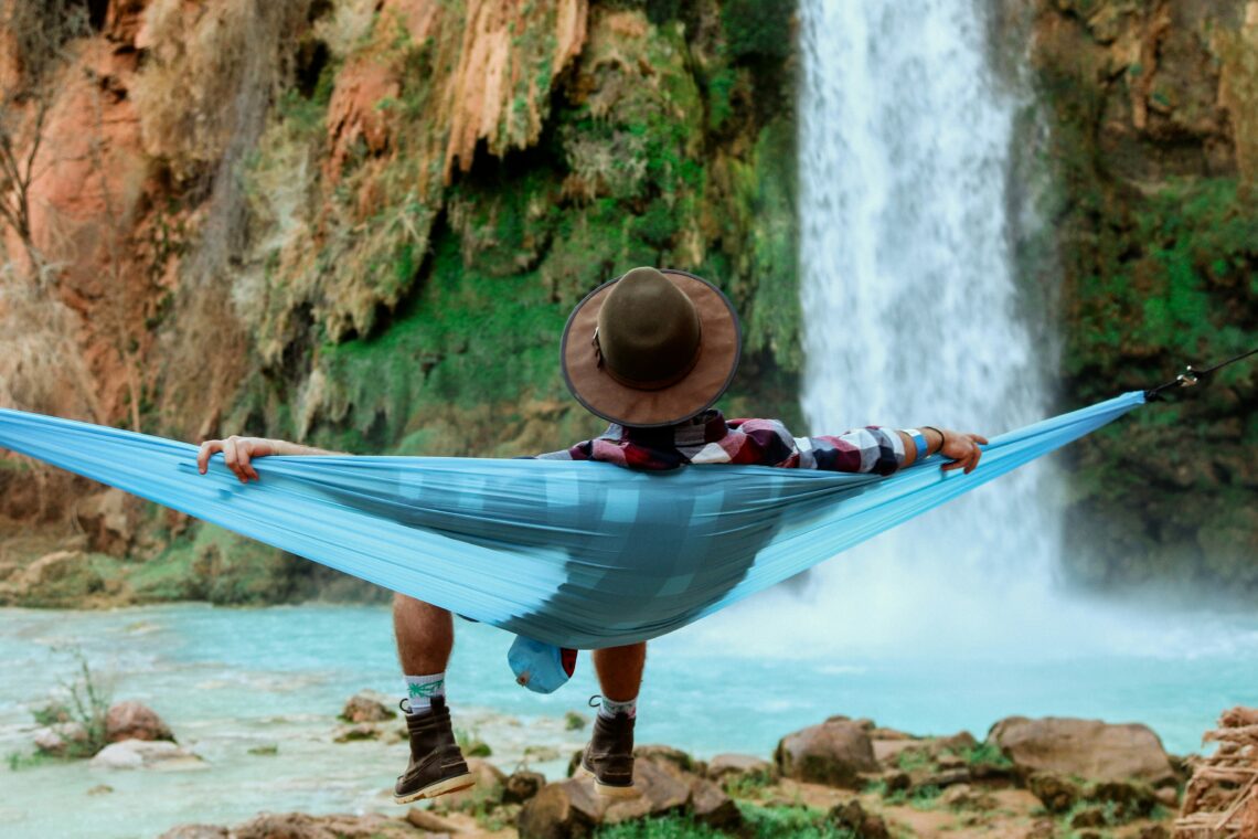 Man in een hangmat met achter hem een waterval