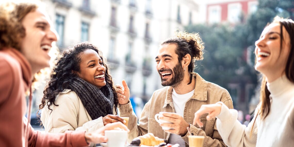 Lachende mensen op een terras Groep mensen die vol vreugde koffie aan het drinken zijn op een terras