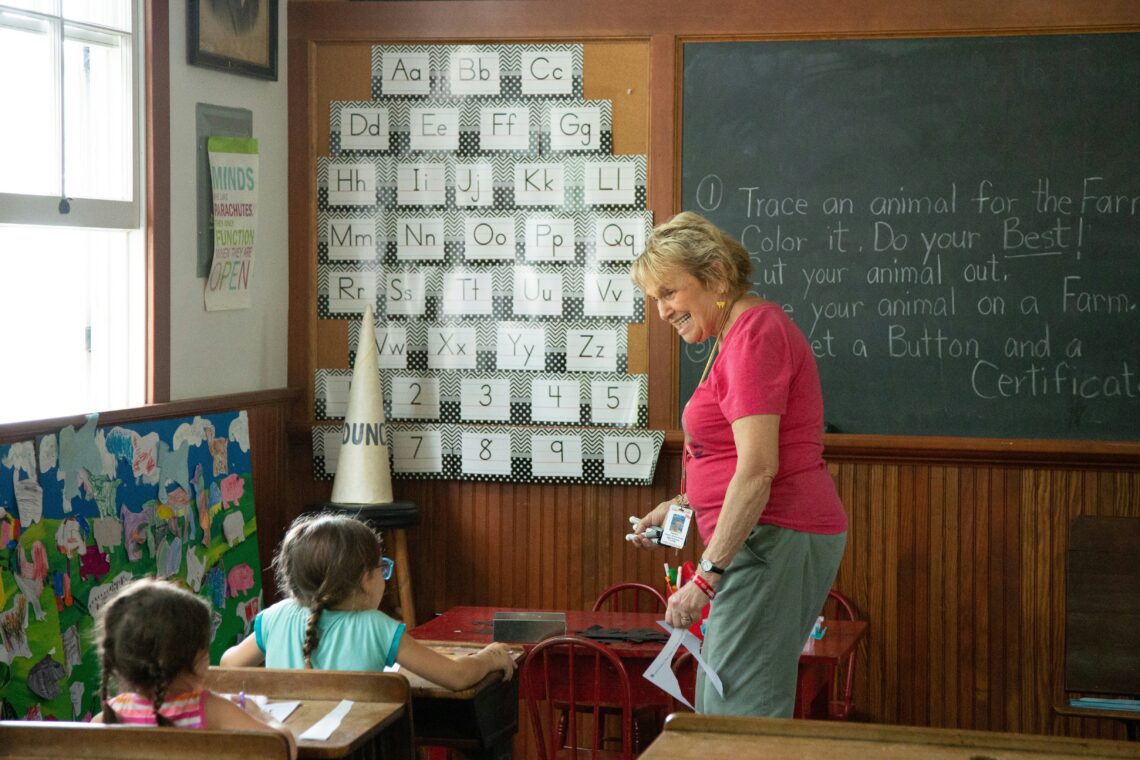 Docent die kinderen aan het leren lezen is.