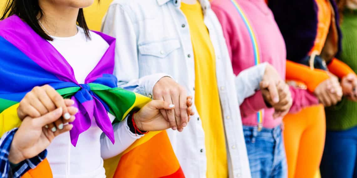 Queer mensen die in een rij hand in hand staan