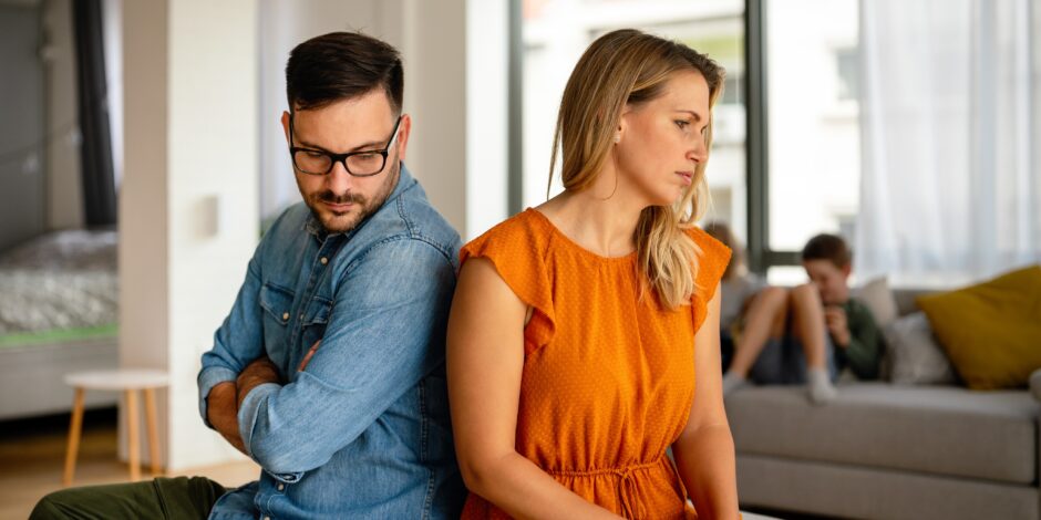 Man en vrouw die met hun ruggen tegen elkaar op de bank zitten