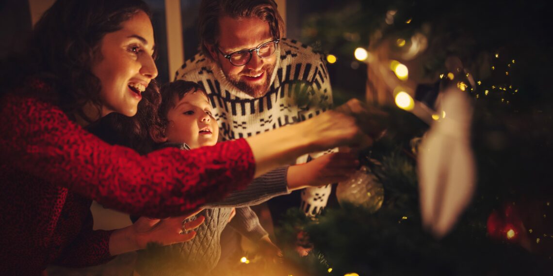 Familie die de kerstboom aan het versieren is