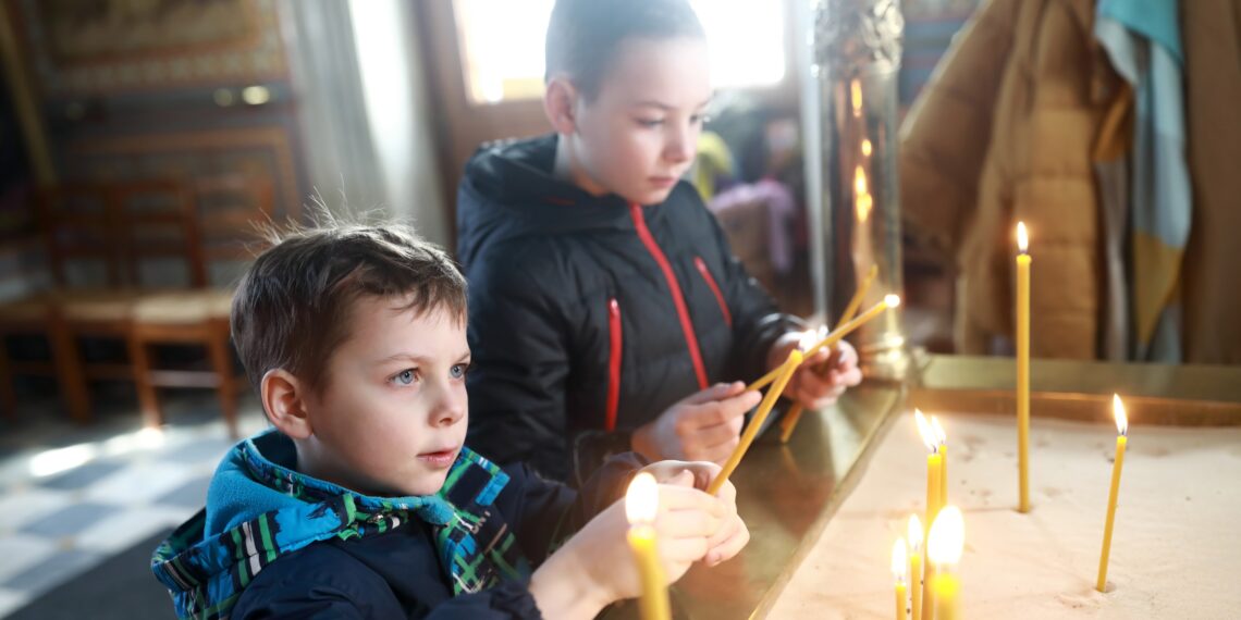 Twee jongetjes die kaarsen aan het aansteken zijn.