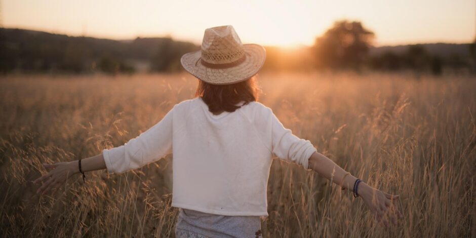 Vrouw die door een grasveld loopt tijdens zonsondergang