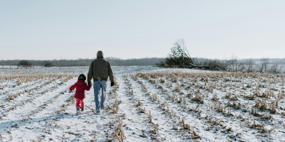 Vader en kind die hand in de sneeuw lopen
