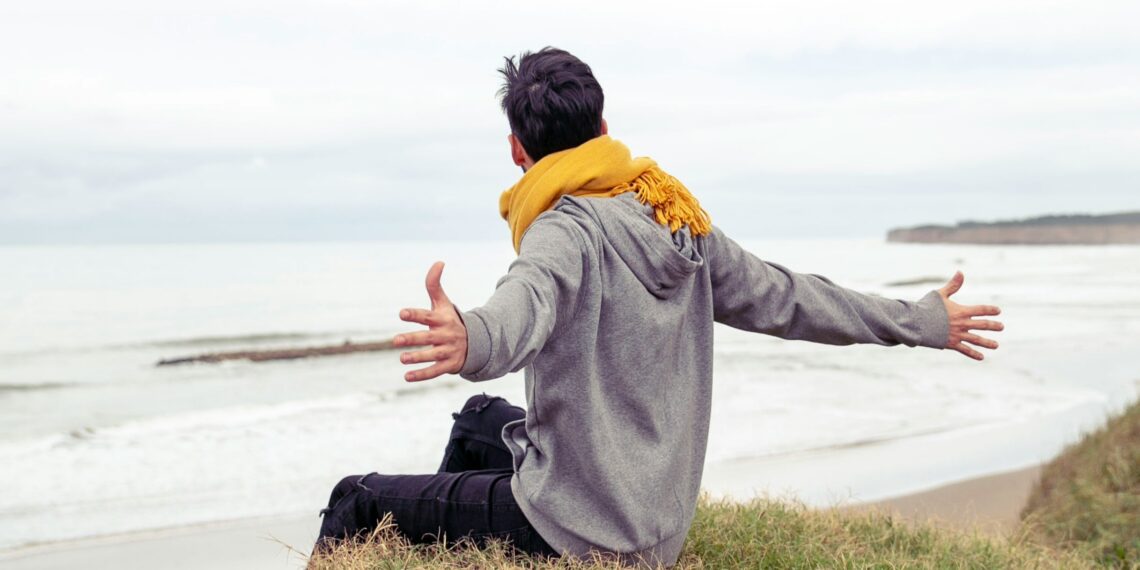 Man die op een rots boven het water zit