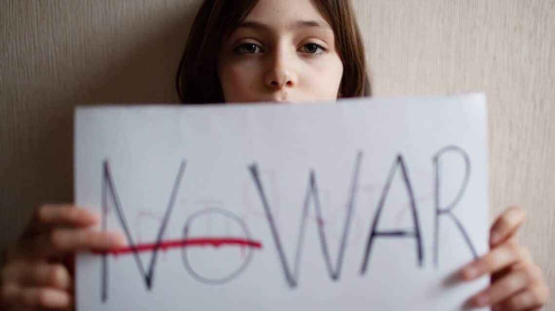 Meisje die een blad vasthoudt met No War erop geschreven met No doorgestreept