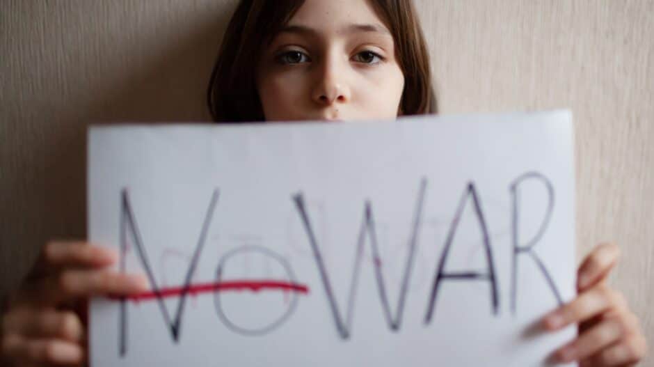 Meisje die een blad vasthoudt met No War erop geschreven met No doorgestreept