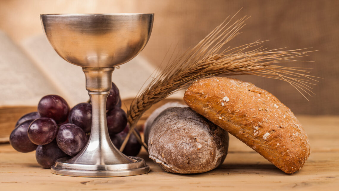 Wijnbeker, tros druiven en brood die op een houten tafel liggen