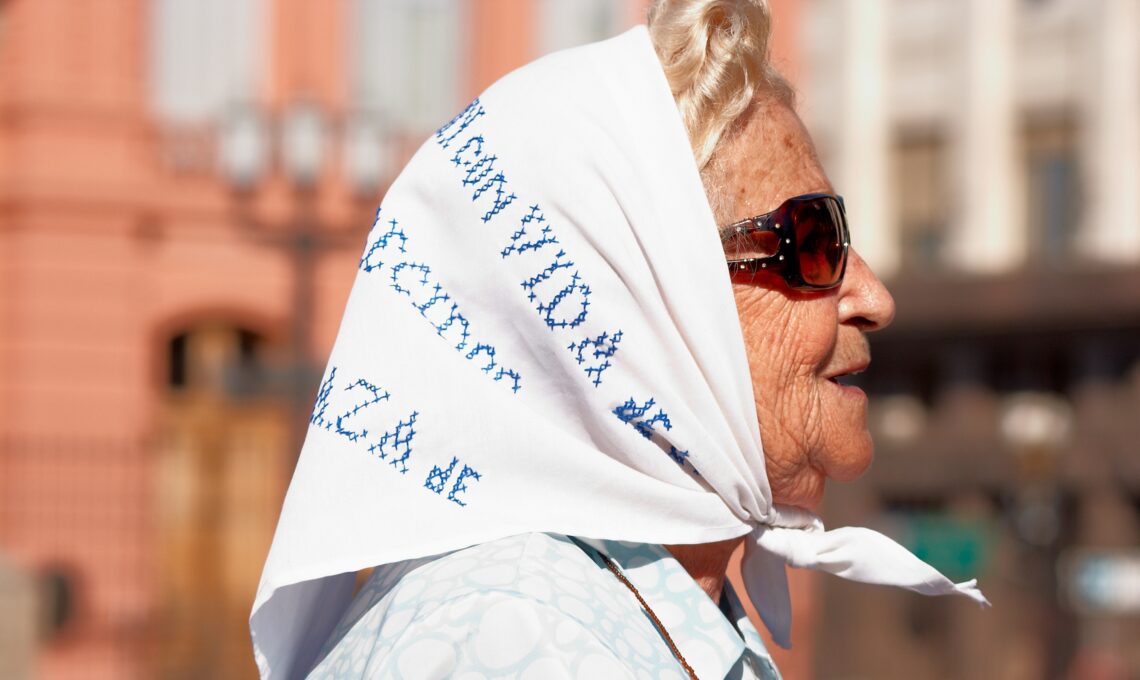 Vrouw met een zonnebril op en met een sjaaltje in haar haar.