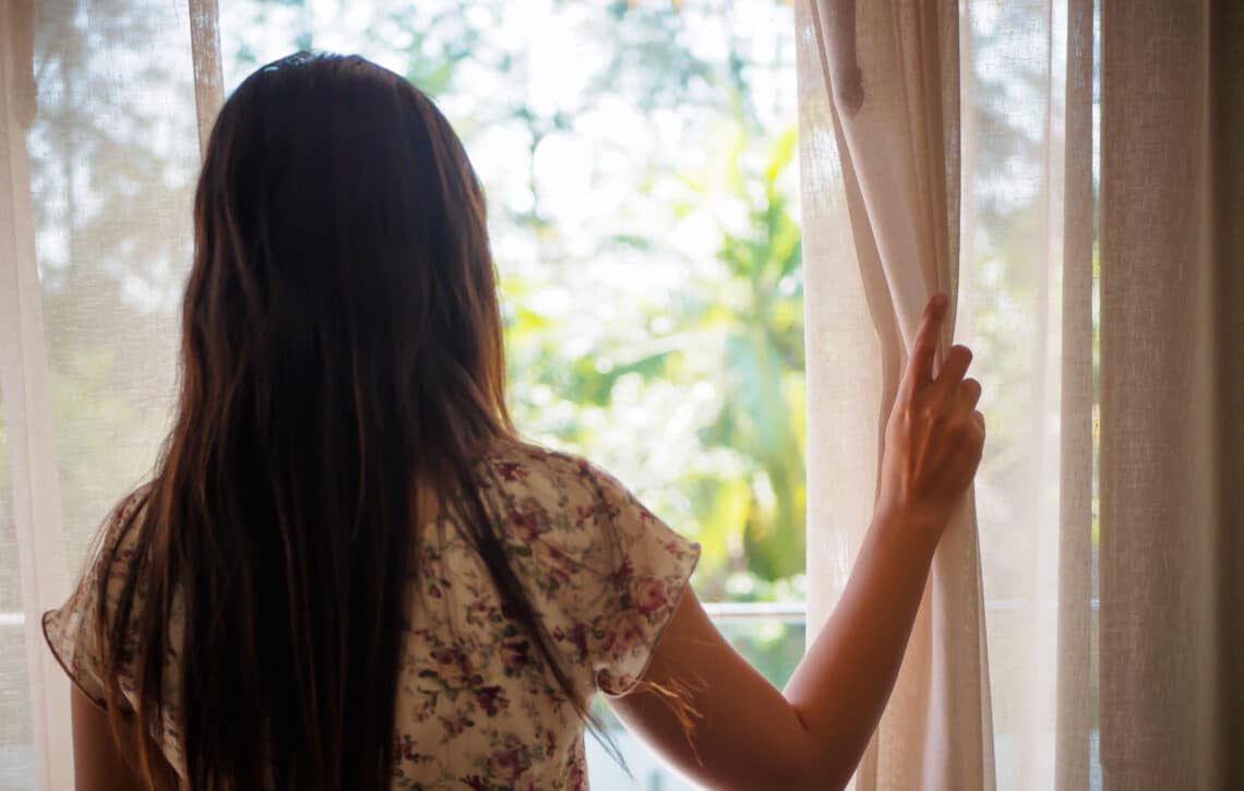 Vrouw die uit het raam naar buiten kijkt