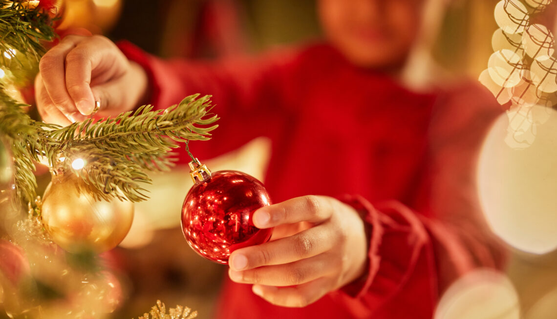 Kind die de kerstboom aan het versieren is