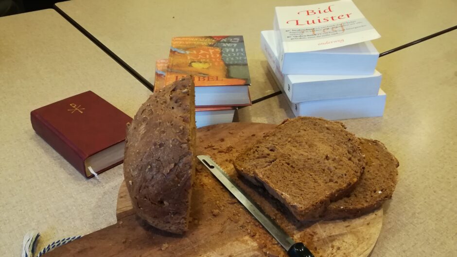 Brood plank met een gesneden brood erop, met daarachter een stapeltje Bijbels