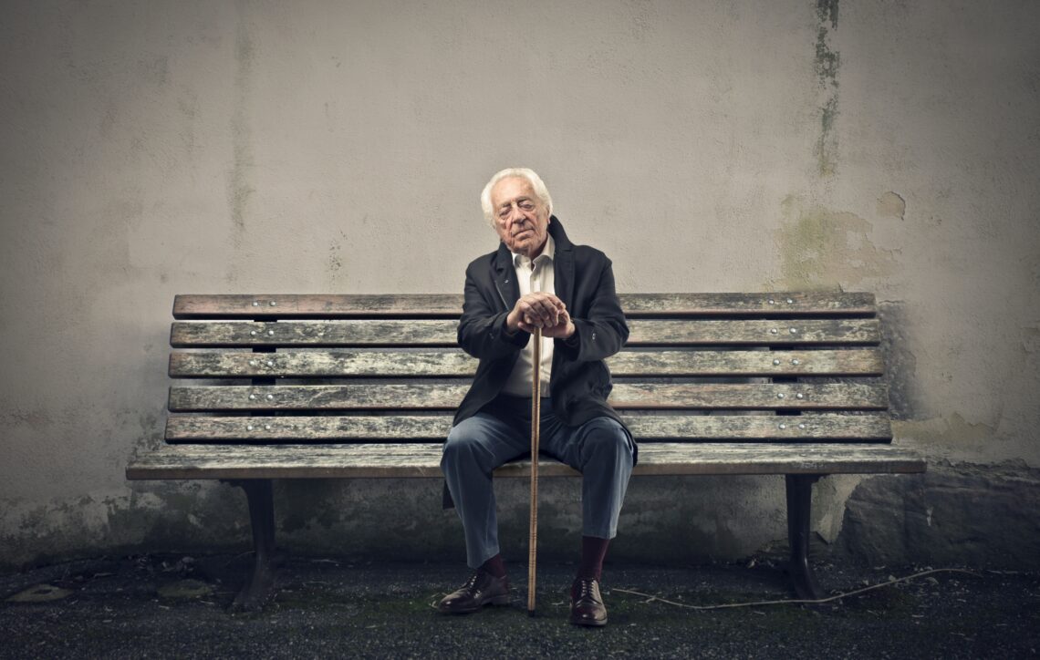 Oude man met wandelstok op versleten bankje