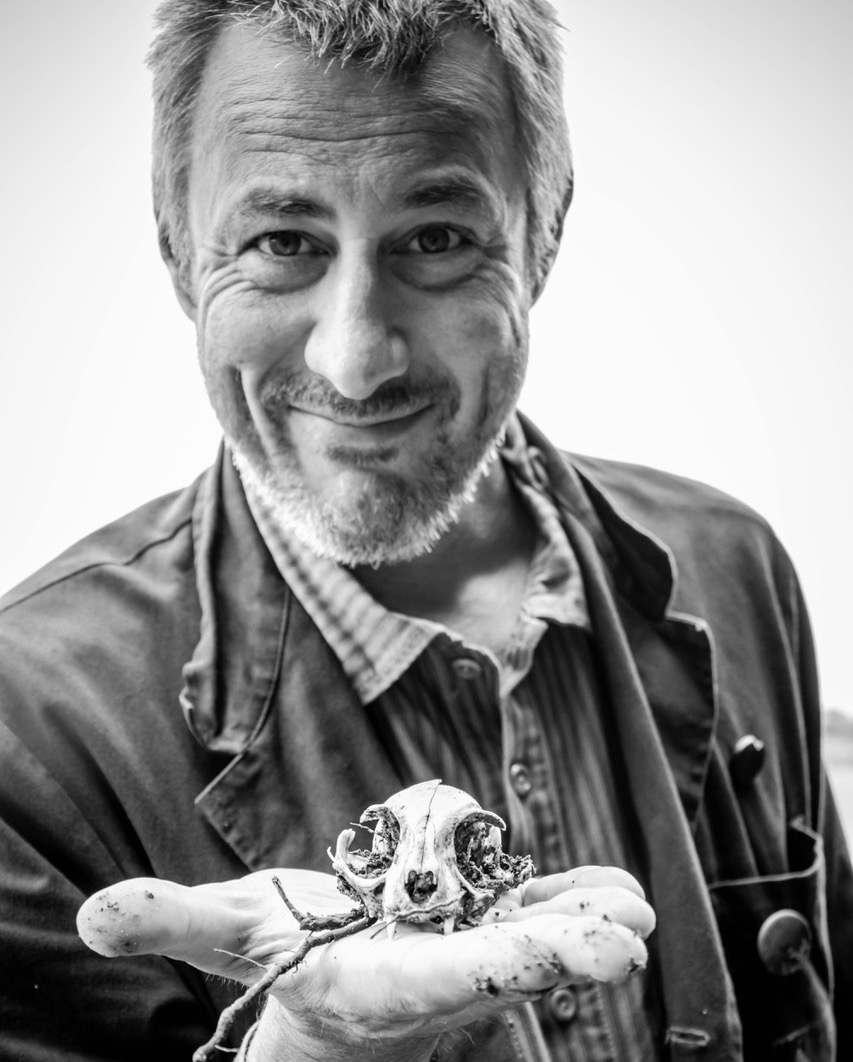 Tonnie Dieleman kijkt grijnzend in de camera en laat een kleine schedel van een dier zien, die hij in zijn hand vasthoudt