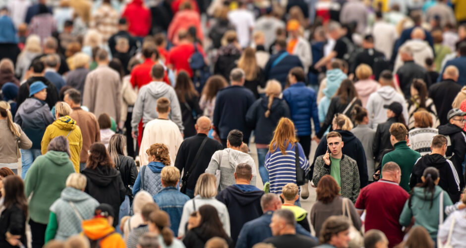 young man is talking on the phone surrounded by a crowd during rush hour in a large metropolis.