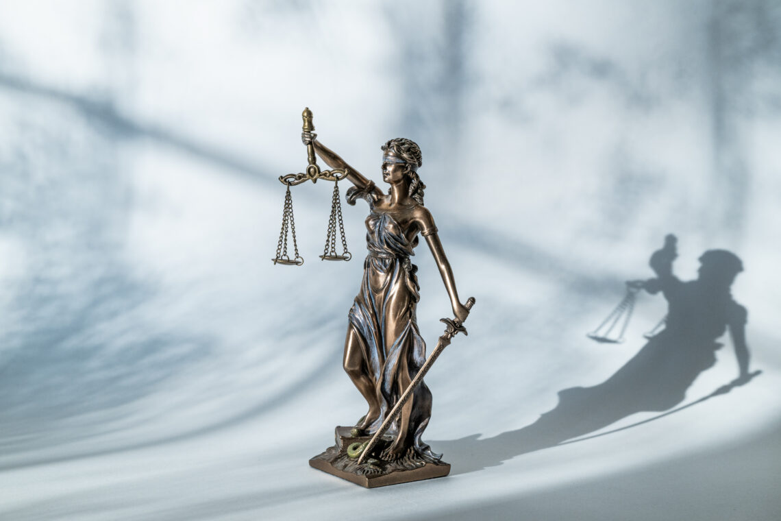 Beeld Vrouwe Justitia met lange schaduw erachter