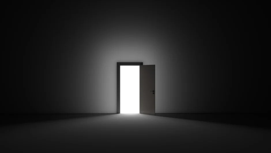 Donkere ruimte met open deur waarachter licht schijnt