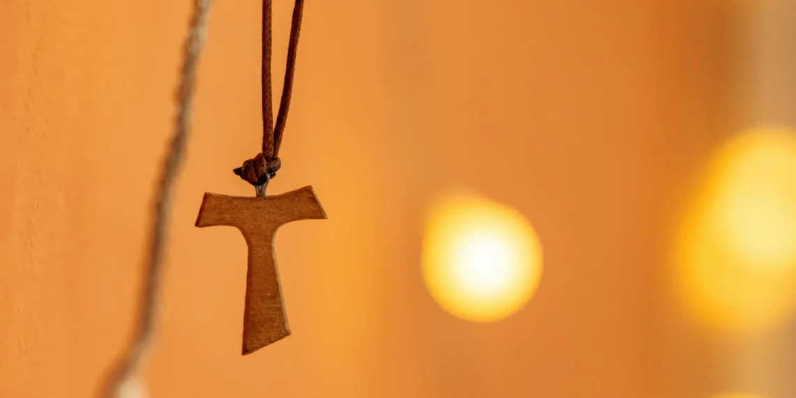 Franciscaans Tau-kruis met lampjes op de achtergrond.