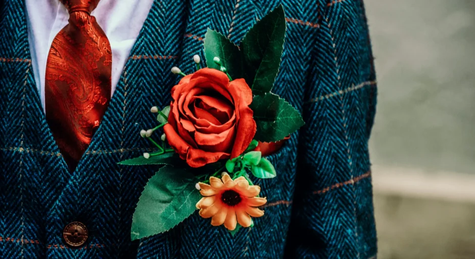 Corsage met rode roos vastgespeld op een jasje van de bruidegom