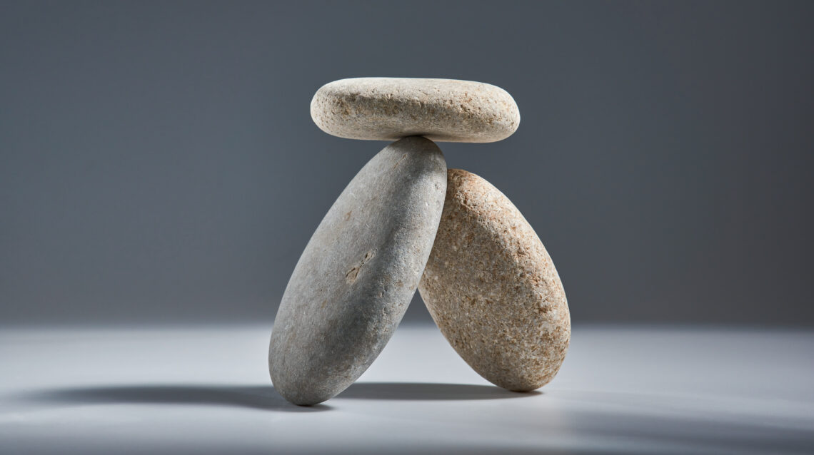 Balancing pyramid of sea pebbles on a gray background, the concept of harmony and balance, heavy and light. Stones in the form of scales with balancing stones.